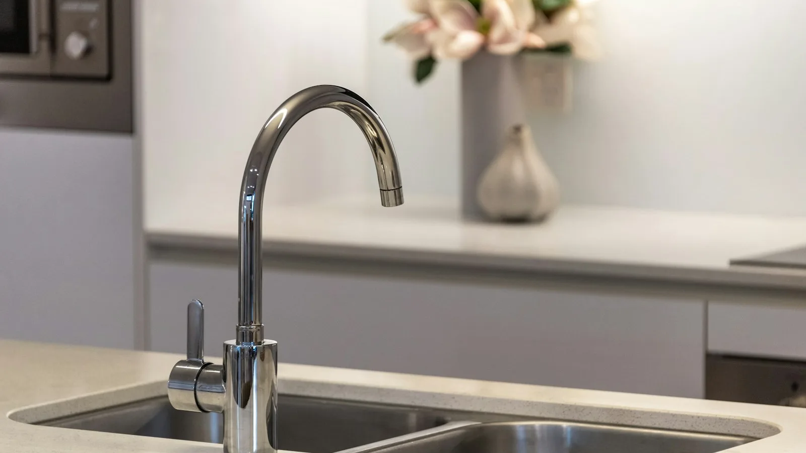 A faucet-mounted water filter dispensing clear water into a glass over a kitchen sink