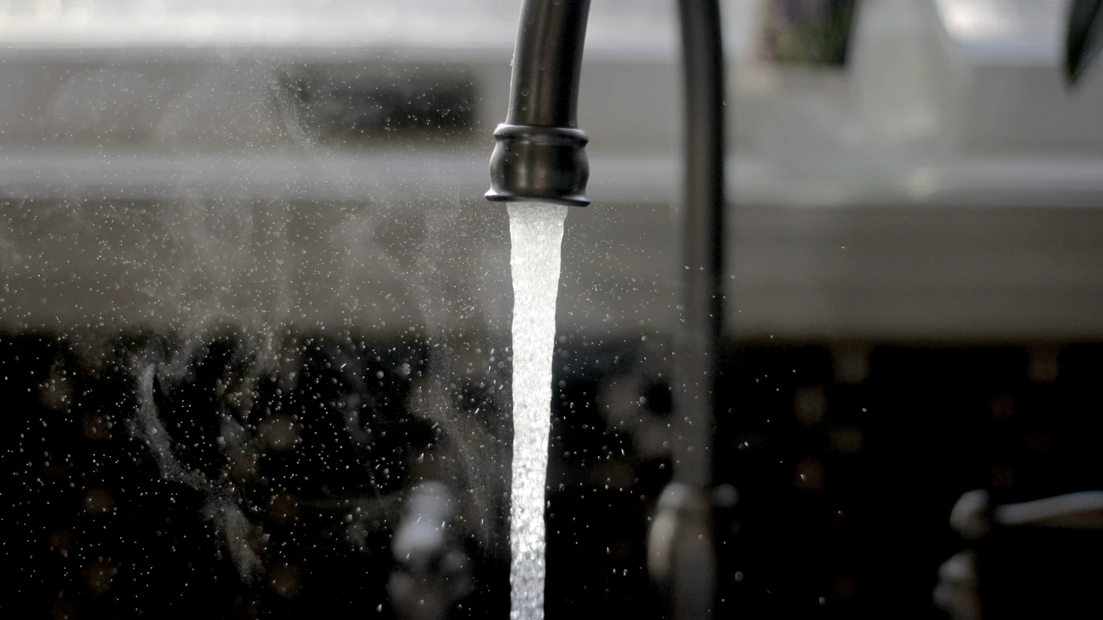Kitchen faucet running water into a sink, illustrating unfiltered tap water that may contain lead